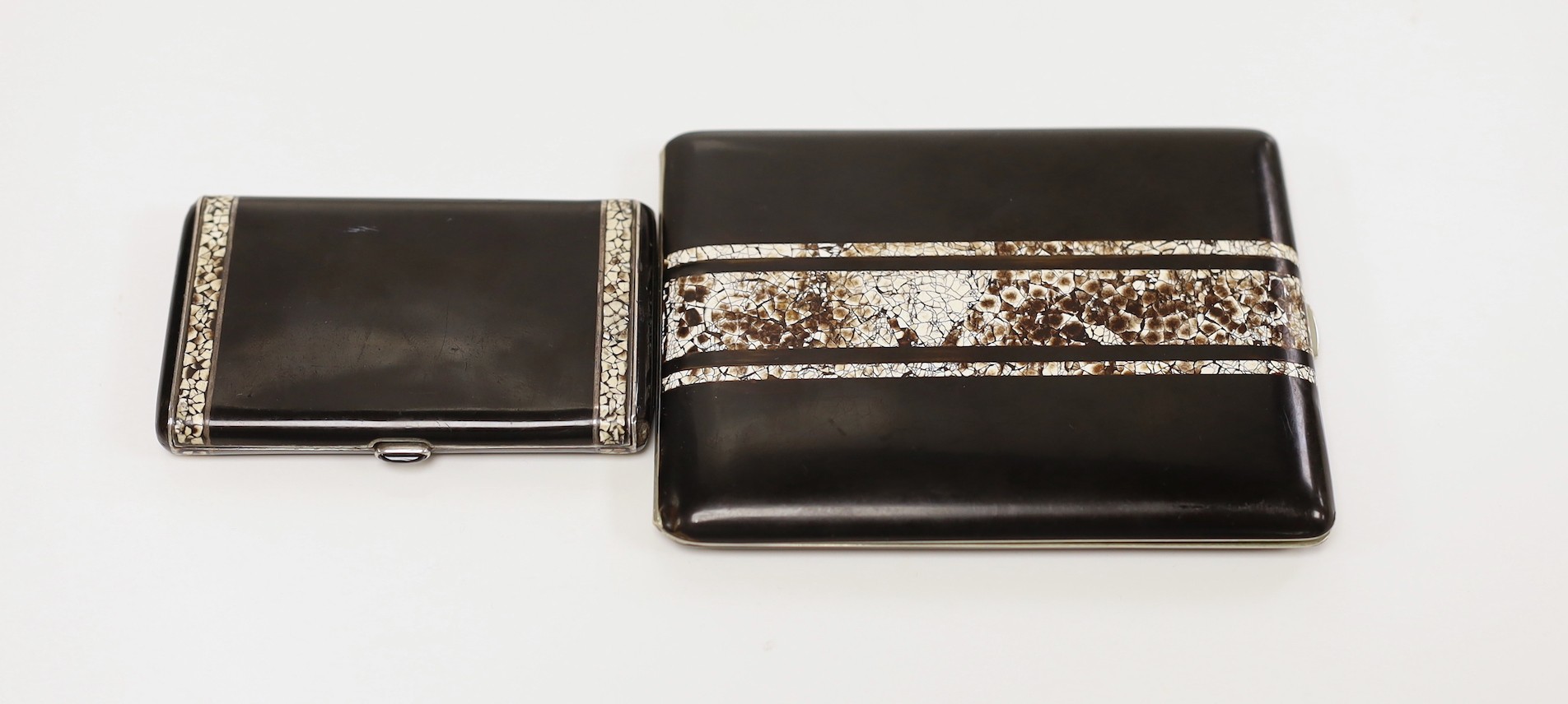 A French Art Deco white metal, black lacquer and eggshell banded cigarette case, with cabochon button, 8cm and one other similar larger cigarette case though apparently unmarked.